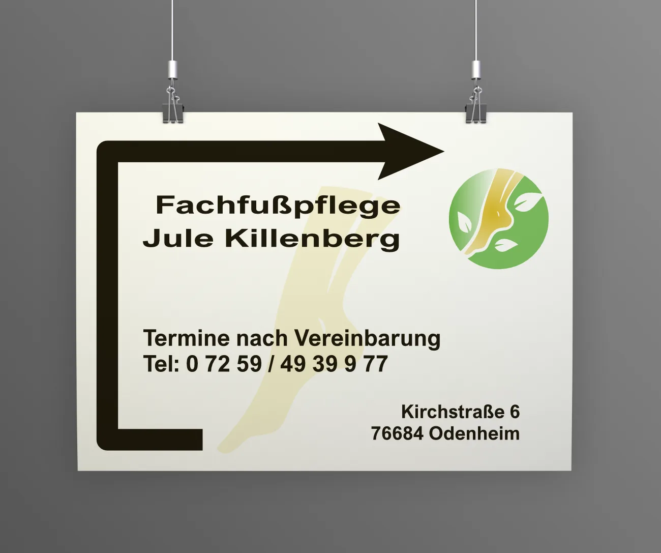 Weißes Hinweisschild an einer grauen Wand mit Pfeil, dem Namen Fachfußpflege Jule Killenberg und der Telefonnummer