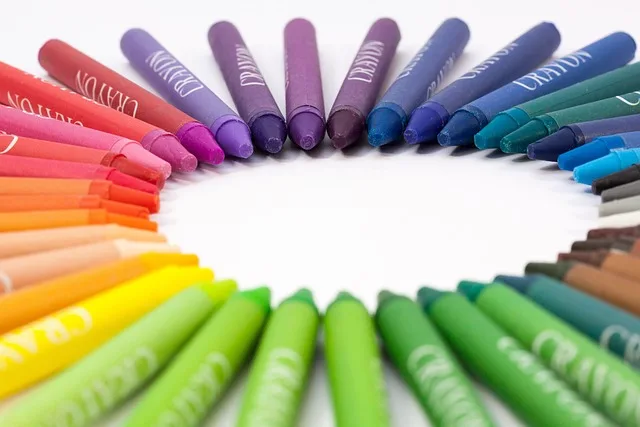 Bunte Wachsmalstifte im Kreis auf weißem Untergrund, nach Farben sortiert